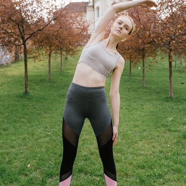 Woman in an energetic yoga pose against a dark background.